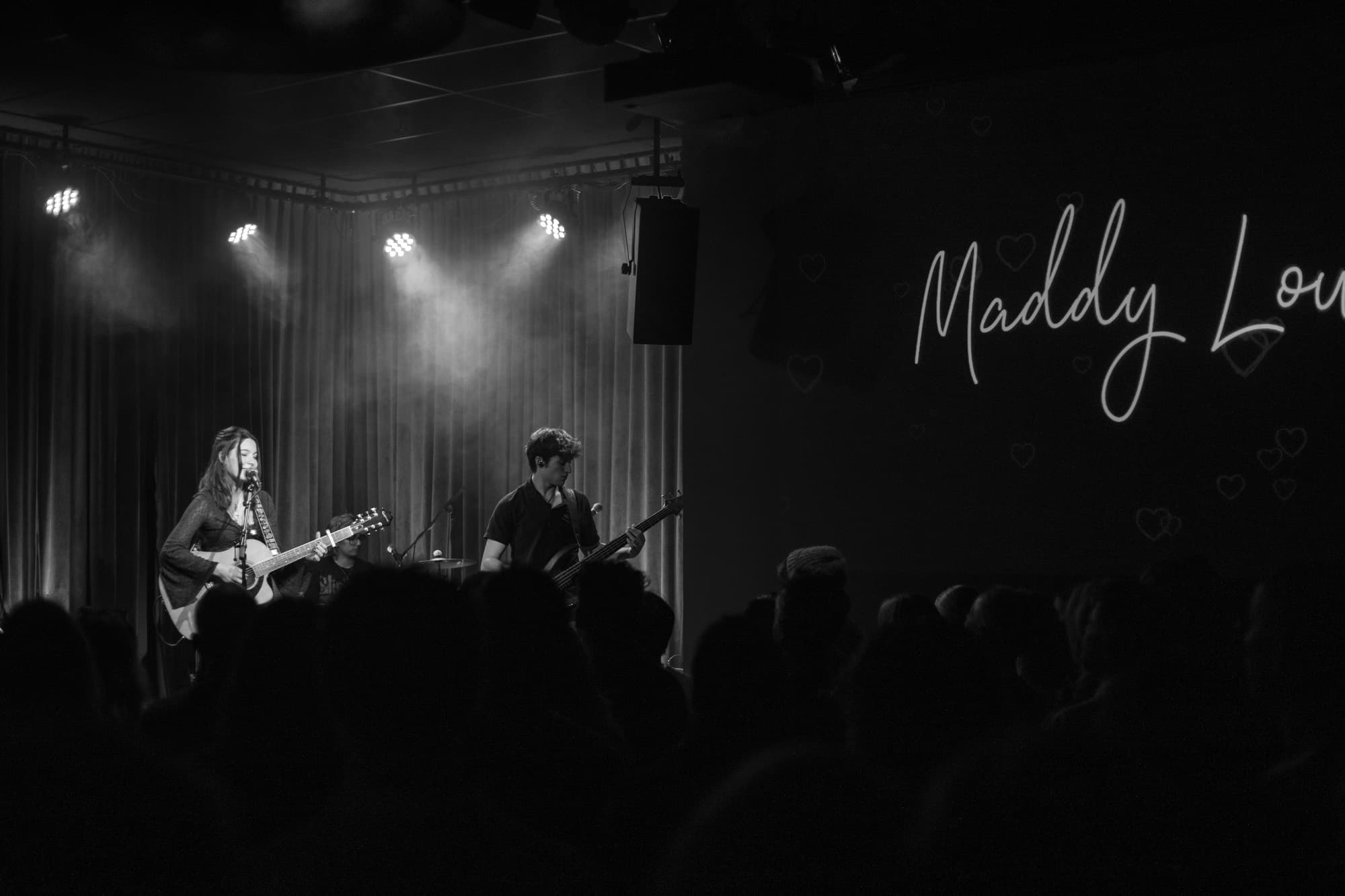 Maddy Low smiling while holding a guitar.